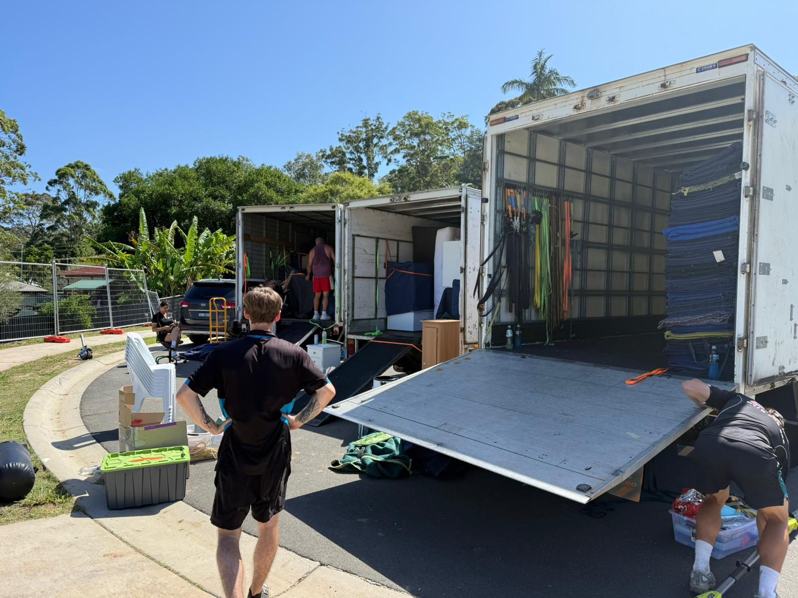 Two removalists loading furniture at the truck tailgate in a driveway